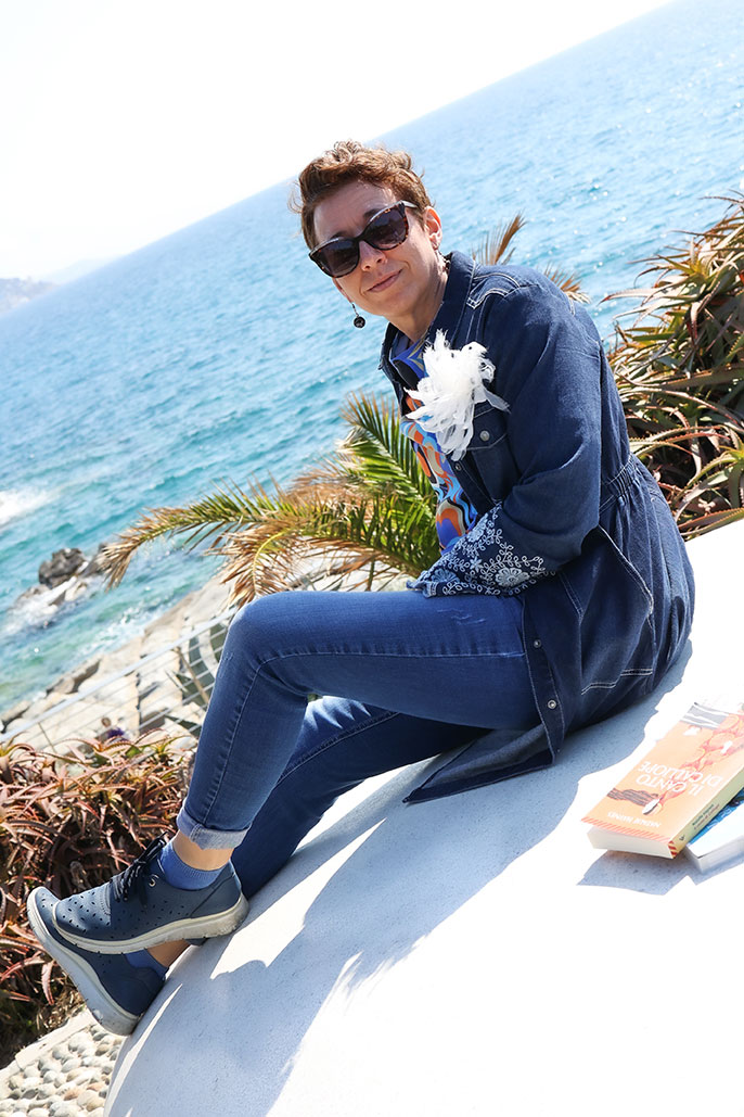 Donna con occhiali da vista e libri con mare sullo sfondo